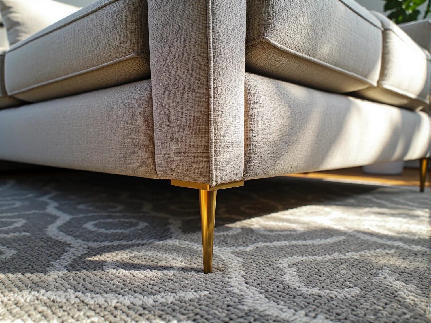 Złote nóżki i ozdobne detale wykończeniowe odnowionej sofy w stylu glamour.